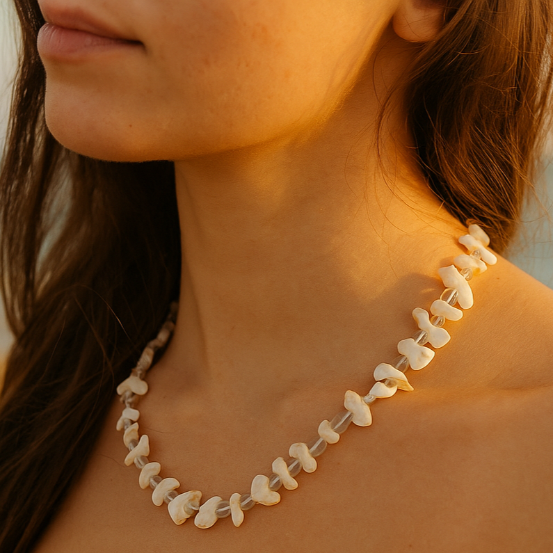 Close-up of a woman wearing a shell necklace with a blurred beach background