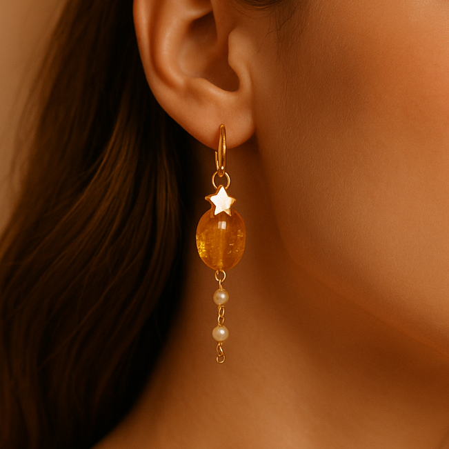 Close-up of a woman wearing amber-colored earrings with a neutral background