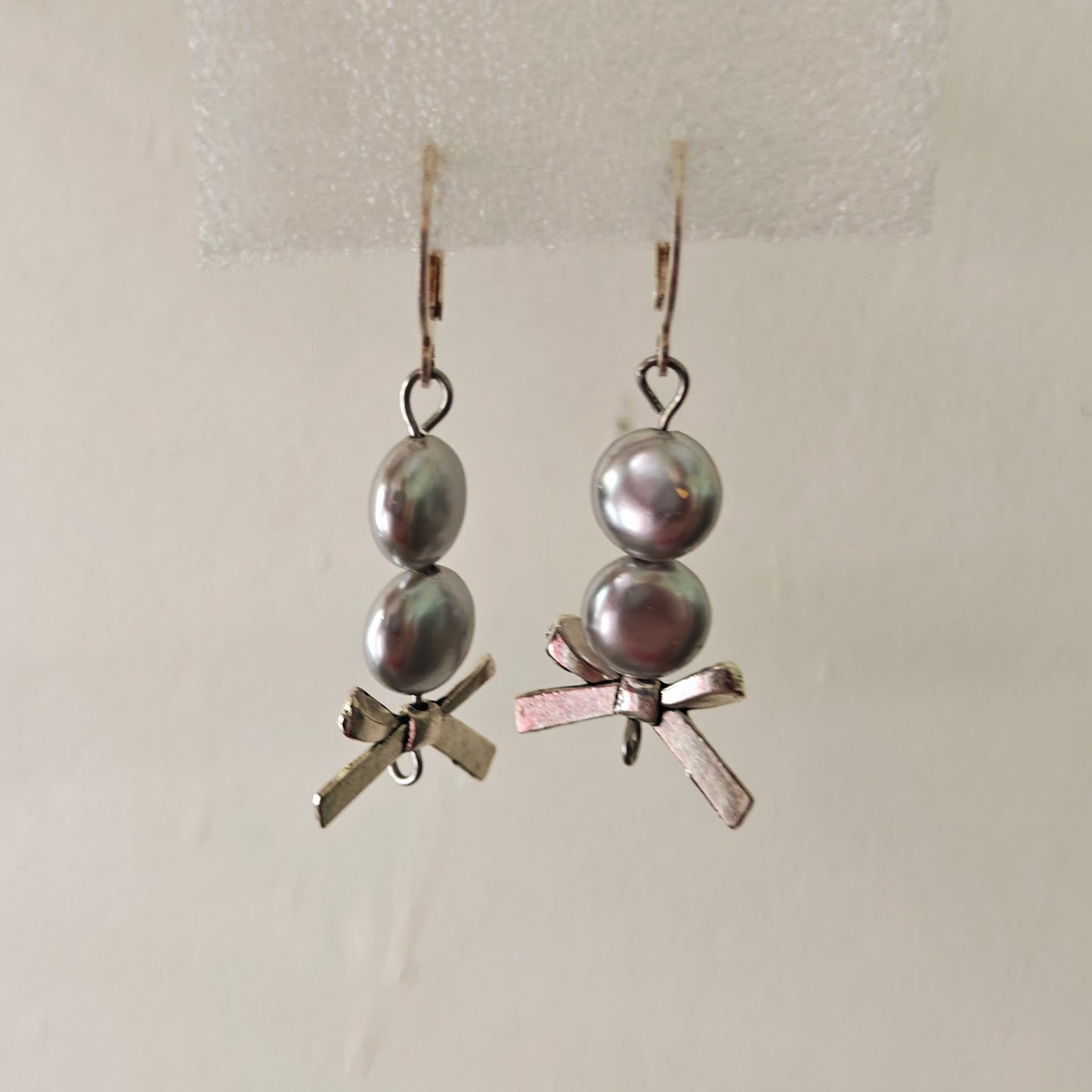 Pair of earrings with pearls and small decorative elements on a light background