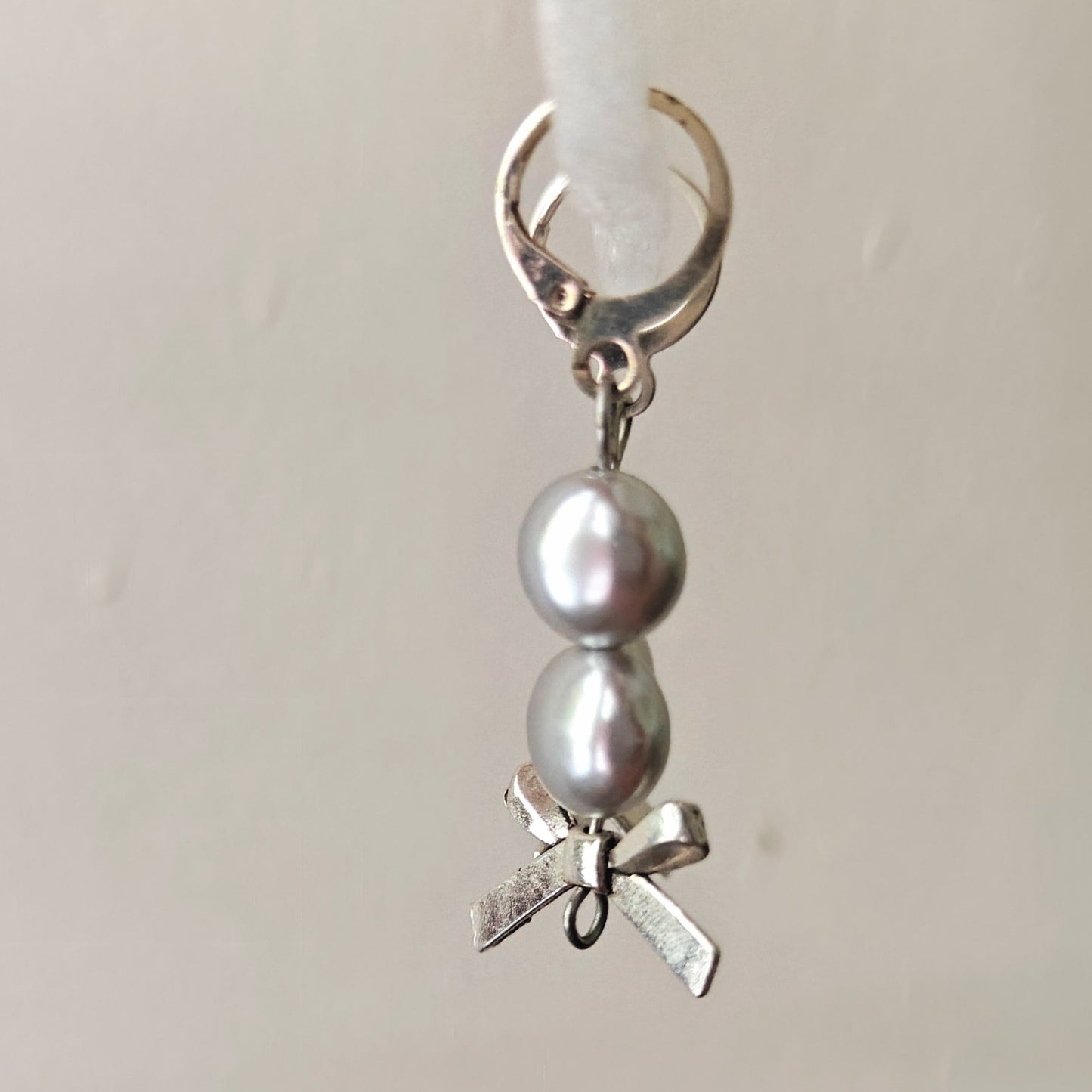 Silver charm with pearls and a bow on a white background