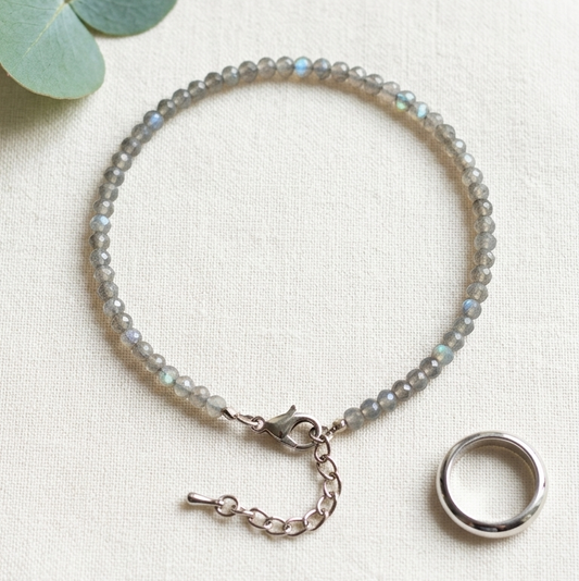 Bracelet with small stones on a white surface with eucalyptus leaves