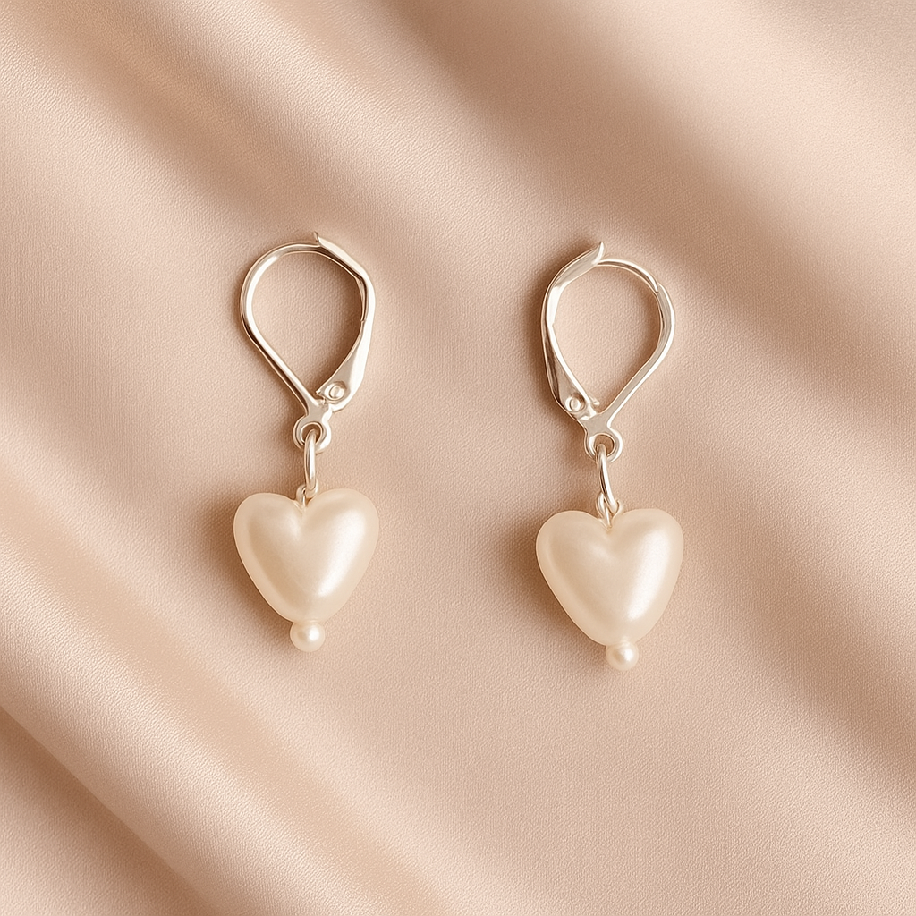 Heart-shaped pearl earrings on a beige fabric background