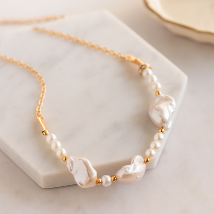 Pearl necklace with gold accents on a marble surface