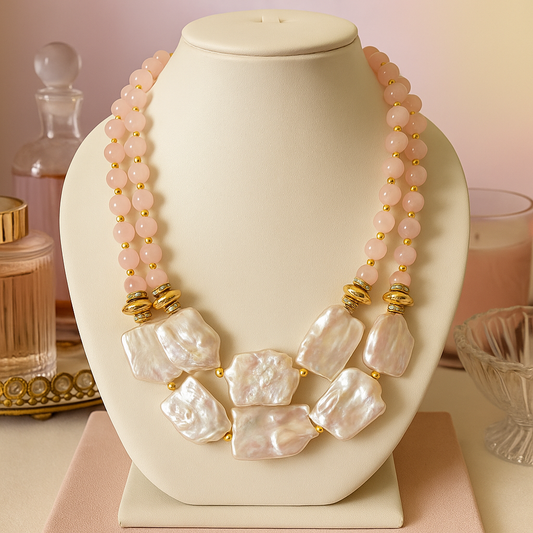 Necklace with pink beads and large white pearls on a decorative stand with a soft background.