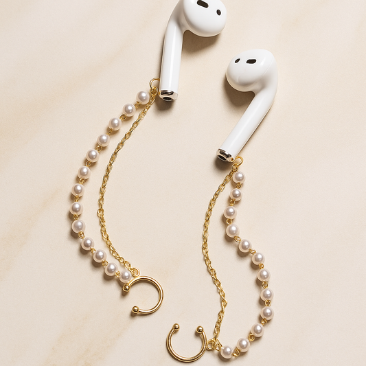 White AirPods with a pearl and gold chain accessory on a beige background