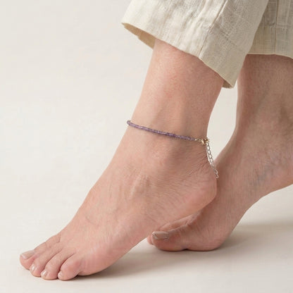 Anchored anklet on a foot against a neutral background