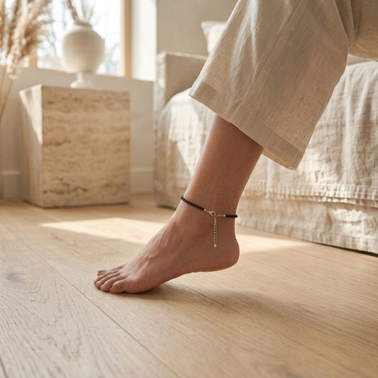 Person wearing a anklet on a wooden floor with a blurred background