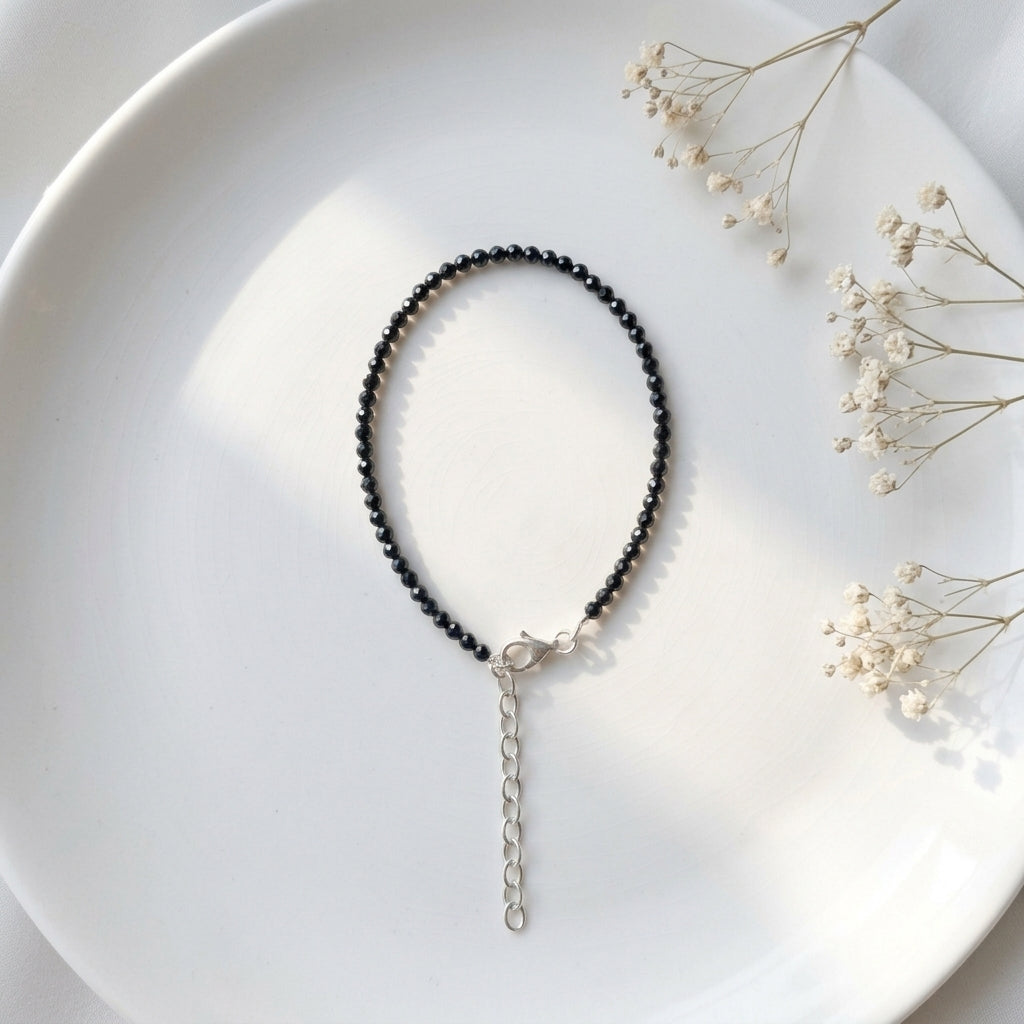 Black beaded necklace on a white plate with dried flowers