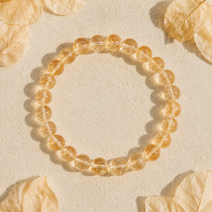 Gold citrine beaded bracelet on a beige background with dried leaves