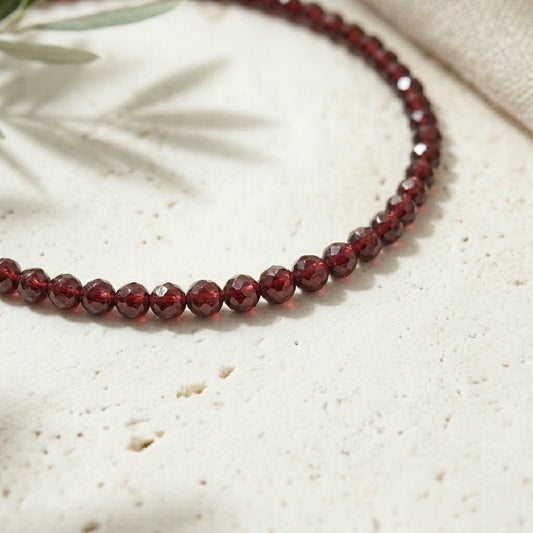 Garnet beaded necklace on a textured beige surface