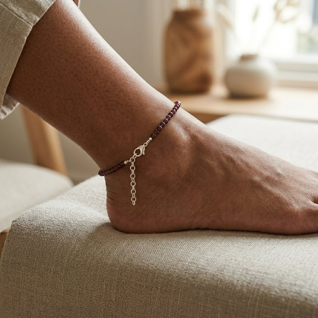 Close-up of a foot wearing a anklet on a soft surface with a blurred background
