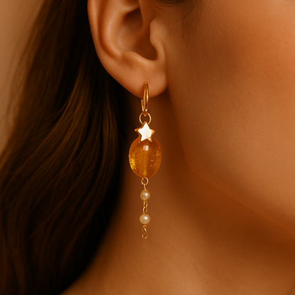 Close-up of a woman wearing amber-colored earrings with a neutral background