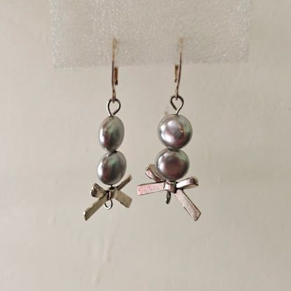 Pair of earrings with pearls and small decorative elements on a light background