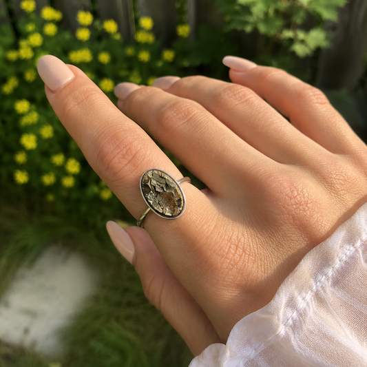 Hand wearing a decorative pyrite ring with a blurred natural background