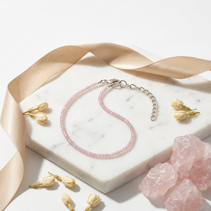 Pink beaded bracelet on a marble surface with pink crystals and dried flowers.