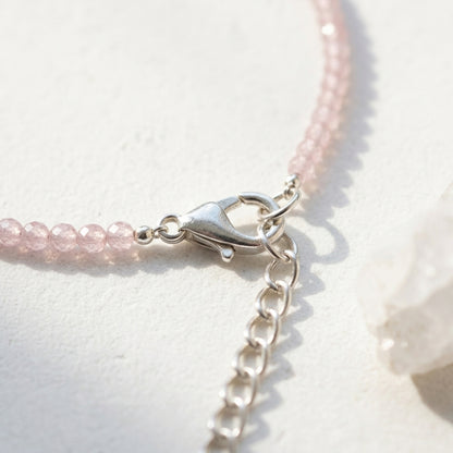 Close-up of a pink beaded bracelet with a silver clasp on a light background