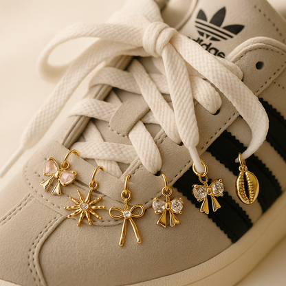 Close-up of a beige Adidas sneaker with gold charms hanging from the laces.