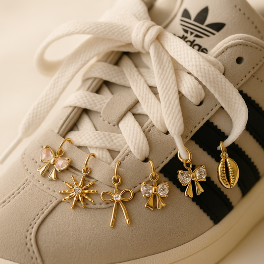Close-up of a beige Adidas sneaker with gold charms hanging from the laces.