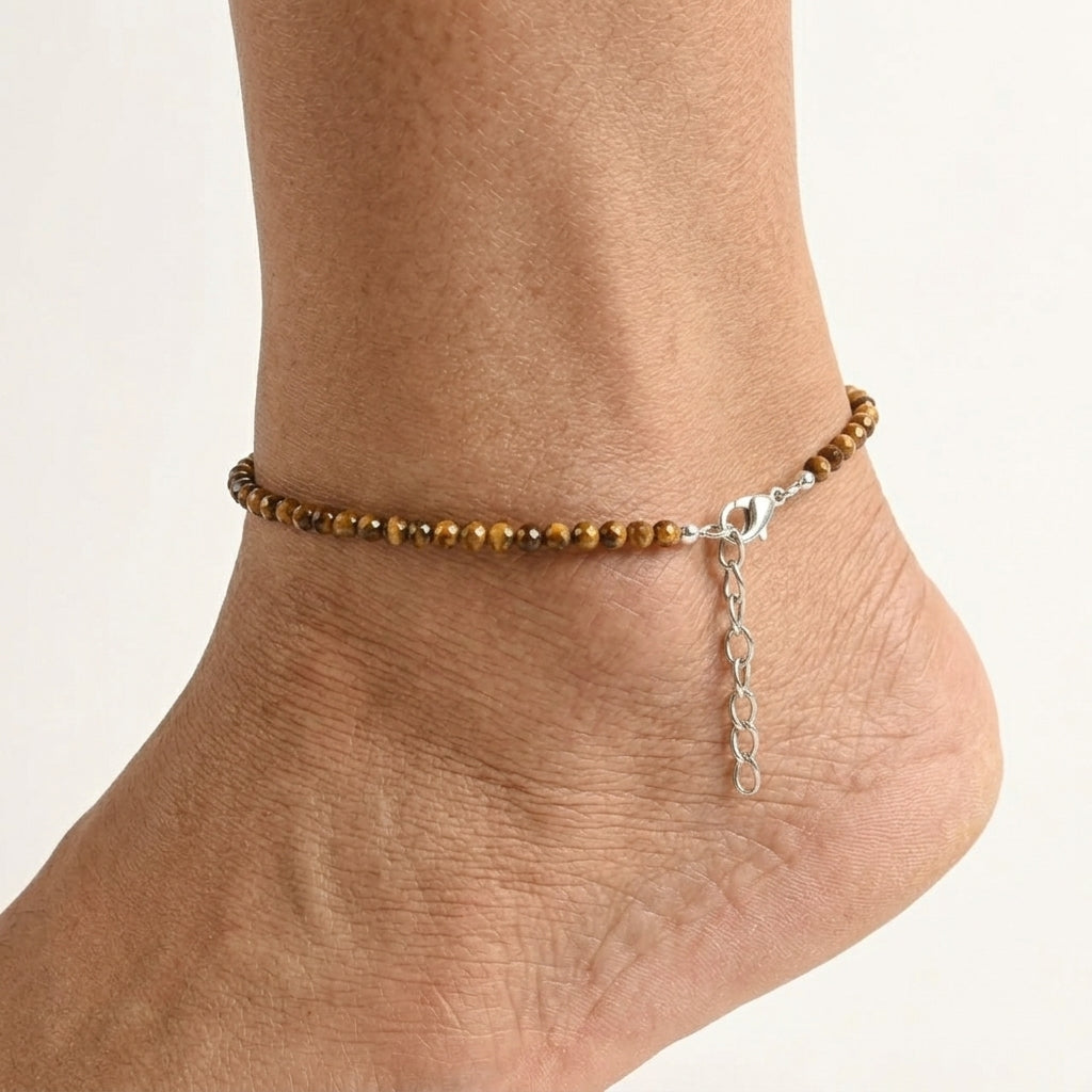Ankle bracelet with brown beads and a chain on a light background