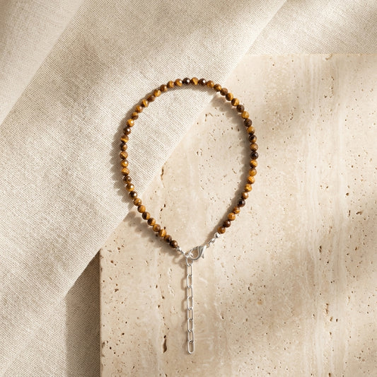Beaded bracelet with a silver clasp on a textured beige surface